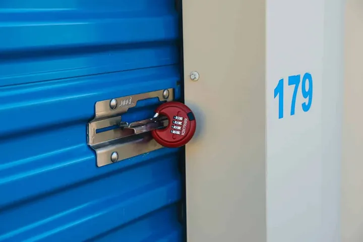 A disc lock on the latch of a blue roll-up storage door